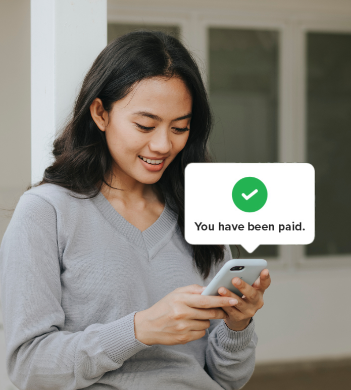 Smiling woman looking at her phone with an on-screen message that says 'You have been paid'