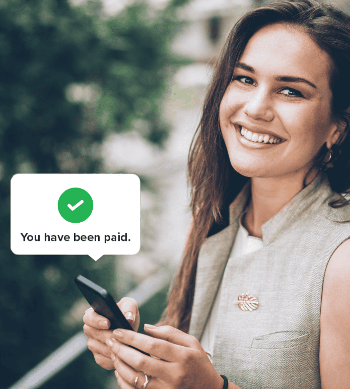 Smiling administrative assistant holding a phone with a notification that says “You have been paid.