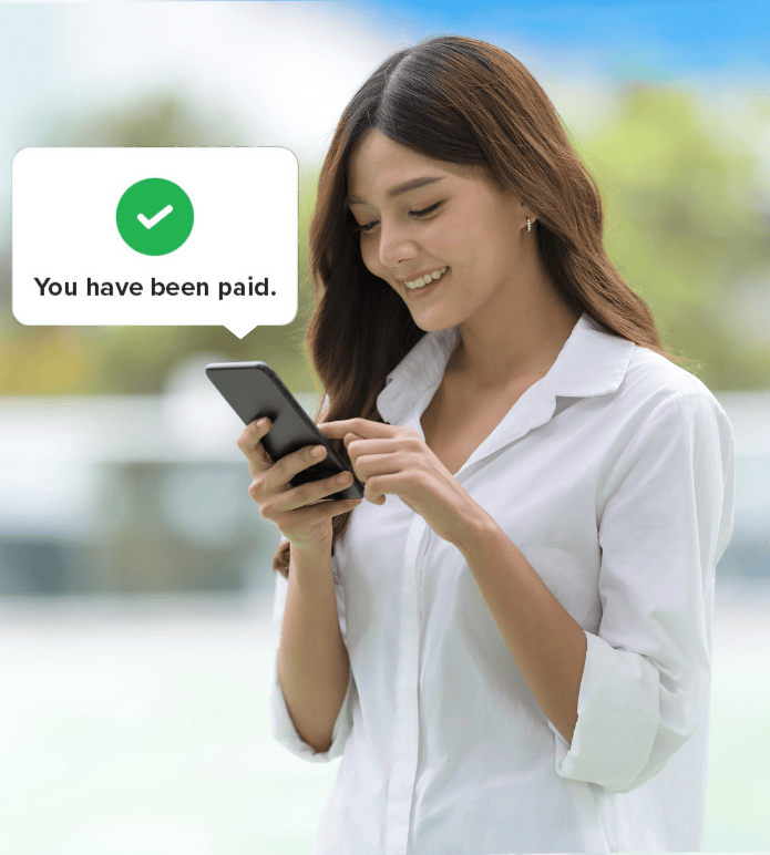 Employee smiling while checking a phone with a payroll confirmation message that says You have been paid